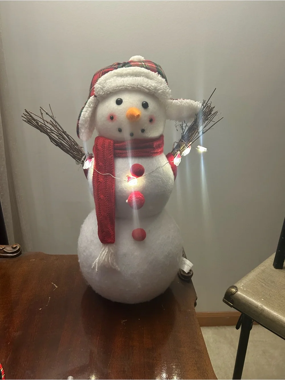 Snowman decoration with twig arms, plaid hat and Santa accent lights New